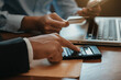 © NINENII - Investors are calculating on calculator investment costs and holding smartphone in hand at home office.
