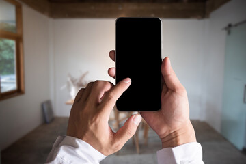 Hand holding  mobile phone with blank white screen in cafe.