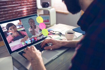 Poster - Caucasian man using laptop for video call, with smiling diverse elementary school pupils on screen