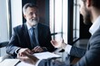 © opolja - Senior and junior businessman discuss something during their meeting, office background.