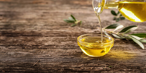 Canvas Print - Olive oil pouring from the pitcher on wooden background