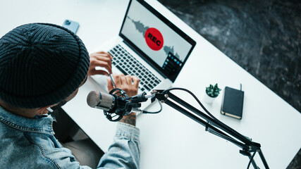 Wall Mural - Mixed race content creator streaming his live podcast using professional microphone at his broadcast studio, top view