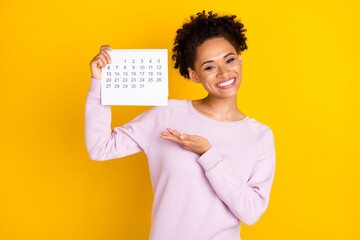 Wall Mural - Photo of charming positive dark skin person hold demonstrate calendar isolated on yellow color background