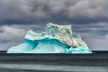 Iceberg Floating In The Sea Off The Coast Of Disko Island, Greenland Under Dark Overcast Sky