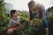 © Halfpoint - Happy little girl with mother working outdoors at community farm.
