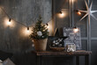 © Svetlana - an element of the design of the New Year's interior in dark color in the loft style with a poster table, a small Christmas tree, light bulbs and decoration
