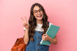 © Asier - Young caucasian student woman isolated on pink background joyful and carefree showing a peace symbol with fingers.