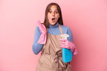Wall Mural - Young caucasian cleaner woman holding spray isolated on pink background surprised and shocked.
