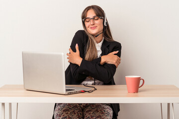 Wall Mural - Young caucasian woman doing telecommuting isolated on white background hugs, smiling carefree and happy.