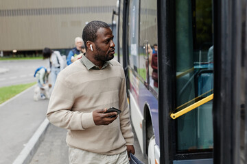 Wall Mural - Waist up portrait of adult African-American man entering bus at bus stop in city, copy space