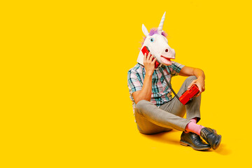 Wall Mural - man with a unicorn mask talks on the phone