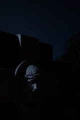 non-existent sculpture cemetery tomb view of marble face at night time with game of light and shadow, vertical photography with star sky background