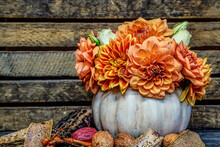 Floral Pumpkin Arrangement. White Pumpkin Filled With A Variety Of Orange And White Flowers. Brown Crate Is Used As The Background. Still Life Image.
