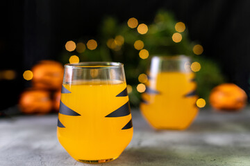 Wall Mural - orange mandarin cocktail in glass with black stripes. Christmas holiday welcome drink. Concept for children new year