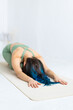 © Вадим Каштанов - Young brunette woman with blue dyed hair practices yoga at home on mat. Spiritual development, self-knowledge and meditation.