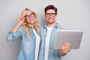 Sticker - Photo of sweet adorable young couple dressed jeans shirts spectacles holding modern gadget isolated grey color background