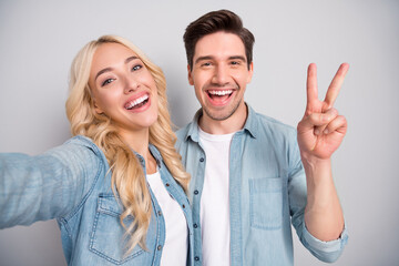 Wall Mural - Photo of young cheerful couple happy positive smile show peace cool v-sign shoot selfie isolated over grey color background