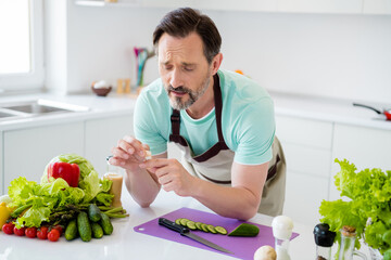 Poster - Photo of troubled mature man cut himself apply plaster finger cry wear apron blue t-shirt home kitchen indoors