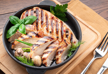 Wall Mural - Roasted chicken fillet and mushrooms with herb in the frying pan on the wooden table close-up.