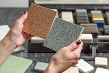 Choice Of Tiles. Female Hands Hold Samples Of Tiles Of Different Colors. Woman In Store Chooses Bathroom Tiles