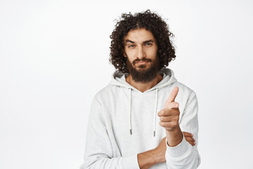 Wall Mural - Handsome middle easter man pointing finger at camera with confident look, inviting you, recruiting people, standing over white background