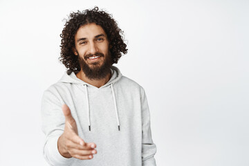 Wall Mural - Handsome smiling young man extend hand for handshake, greeting you, saying hello, nice to meet you gesture, white background