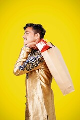 Canvas Print - Indian man in ethnic wear with shopping bags, isolated over yellow background