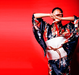 Poster - young pretty geisha on red background posing in kimono, oriental