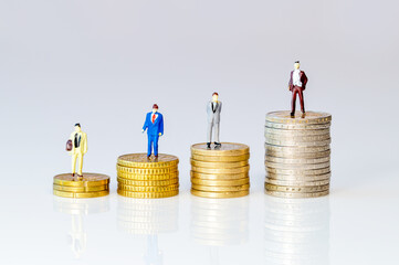 Investment concept. Business toy people standing on stacks of Euro coins. Symbol for increasing or reduction expenses for salary. Miniature businessman on increasing high stack of coins, money. 