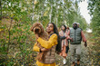 © pressmaster - Girl holding the dog on her hands while walking in the autumn forest together with her family