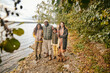 © pressmaster - Portrait of happy family of four embracing and smiling at camera while walking together in autumn forest