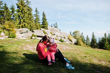 Charming Motherly Love. Mother With Daughter Sit On Mountains Against Stone Rocks.