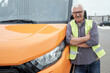 © pressmaster - Happy mature bus driver standing by transport and looking at you in urban environment