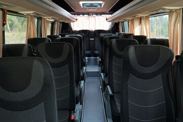 Two rows of grey and balck double seats and long aisle between them inside intercity bus