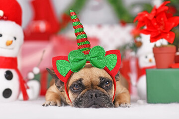 Wall Mural - French Bulldog dog with Christmas unicorn headband in front of seasonal decoration