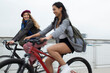 © Martin Barraud/Caia Image - Happy young women friends riding bicycles on bridge