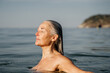 © Alba Vitta/Stocksy - Portrait of beautiful mature woman swimming in the sea