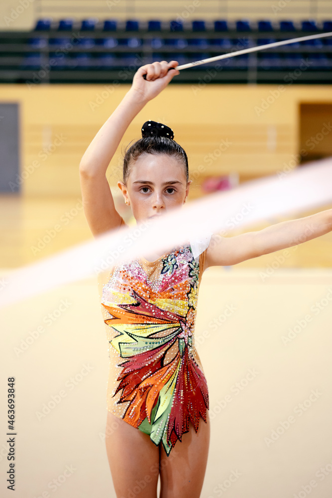 Spining Ribbon Front view of a young girl athlete rhythmic gymnastic exercising ...