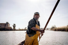 Front View Of A Fisherman Standing In A Boat Using A Push Pole 