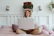 © Sergey Narevskih/Stocksy - Woman with stack of clothes using laptop