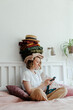 © Sergey Narevskih/Stocksy - Woman with stack of clothes using smartphone