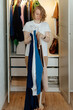© Sergey Narevskih/Stocksy - Woman holding hangers near wardrobe