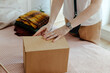 © Sergey Narevskih/Stocksy - Woman packing wear in box for delivery