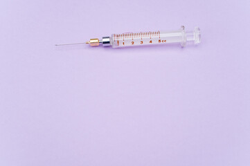 isolated sterilized glass injection syringe on  a lilac paper background