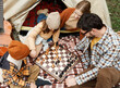 © JenkoAtaman - Happy smiling family playing chess game at campsite during camping trip in nature