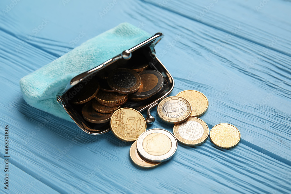 Small wallet with coins on blue wooden background