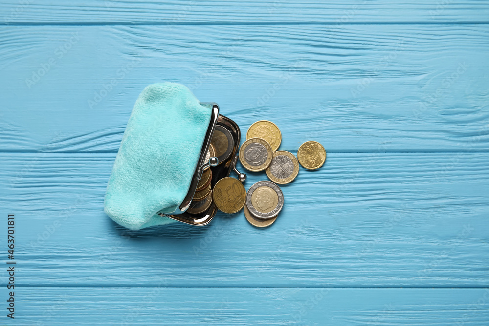 Small wallet with coins on blue wooden background