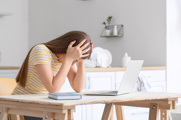 Sticker - Young woman working with laptop at table in kitchen