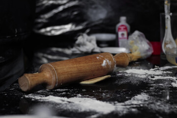 Wall Mural - Closeup of a wooden rolling pin on top of the dough with flour in the foreground