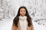 Fototapeta Koty - Cute Asian Girl Standing Smiling in WInter Forest. Snowy Winter Day. Lovely Girl